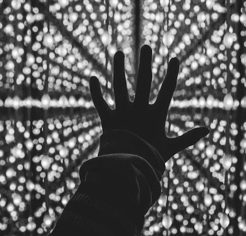 Silhouette of human hand against bright lights